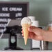 A hand holding a JOY pointed bottom ice cream cone