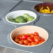 A Cambro crock holder holding a tray of vegetables including broccoli and cherry tomatoes on a counter.