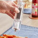 A hand using a Choice 7" Acrylic Pepper Mill to season fries on a table in a home kitchen.