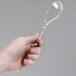 A hand holding a clear plastic Sabert serving spoon.