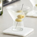 A counter with two Acopa martini glasses filled with liquid and olives.