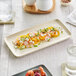 A rectangular white Acopa Pangea porcelain platter with salad and shrimp on it.