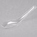 A WNA Comet clear plastic Asian soup spoon on a white surface.