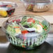 A salad in a Dart clear plastic bowl with a dome lid.
