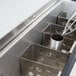 A stainless steel Nemco Divider for an ice cream dipper well on a counter.