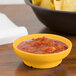A GET Tropical Yellow salsa dish next to a bowl of salsa and chips on a table.
