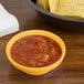 A bowl of salsa and a bowl of chips next to a bowl of tortilla chips on a table.