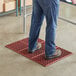 A person standing on a red Choice anti-fatigue floor mat.