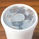 A Dart foam cup with a translucent lid and a straw slot full of liquid.