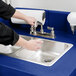 A person washing their hands in a navy blue Cambro CamKiosk sink.