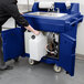 A person pushing a navy blue Cambro hand sink cart with a white and blue sink.