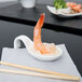An Arcoroc china spoon with rice and shrimp on it.