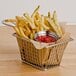 A basket of french fries with ketchup on a table.