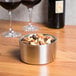 An American Metalcraft stainless steel wine coaster holding a bowl of nuts and raisins on a table with wine glasses.