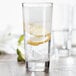 A Fortessa Basics Elixir highball glass filled with water, ice, and a lemon slice.