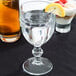 A Libbey Gibraltar goblet filled with water and a lemon wedge.