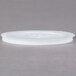 A translucent plastic lid with straw slot on a gray surface.
