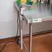 An Edlund stainless steel table with a metal table clamp on it.