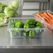 A Rubbermaid clear polycarbonate food storage container filled with carrots and other vegetables.