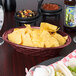 A bowl of tortilla chips and a black oval weave basket filled with food on a table.