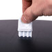 A hand using a black San Jamar Tear-N-Dry paper towel dispenser to clean a surface.