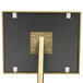 A metal pole with a gold square frame on a black surface.