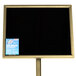 A black marker board with brass accents and blue and white writing on it.
