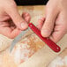 A person's hands using a Victorinox aluminum folding bread lame to cut dough.
