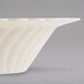 A Fineline Flairware ivory plastic bowl with a curved edge.