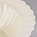 A Fineline Flairware ivory plastic bowl with a scalloped edge.