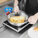 A person cooking a French omelet in a Vollrath Centurion pan.