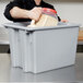 A man pouring food into a Rubbermaid Palletote box.