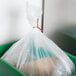A plastic bag in a green bin secured with a red Bedford Industries Inc. twist tie.