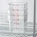 Cambro CamSquares Classic clear polycarbonate food storage containers on a metal rack.