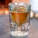 A Libbey fluted shot glass with a .75 oz. pour line filled with brown liquid.