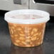 A Pactiv translucent plastic deli container filled with beans on a counter.