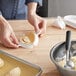 A person using a white plastic dumpling maker to press dough.