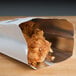 A Bagcraft Packaging foil bag with a "Flame Pak" design holding fried chicken.