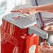 A person using a Heinz automatic touchless pump lid to pour a drink into a cup.