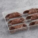 A plastic container of large chocolate cannoli shells.