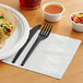 A plate of tacos with a fork and knife on a bamboo EcoChoice napkin.