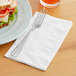 A fork and knife on an EcoChoice bamboo dinner napkin next to a sandwich.