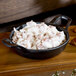 An American Metalcraft pre-seasoned cast iron casserole dish filled with food on a table.