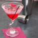 A Libbey martini glass with a red drink and a straw in it.