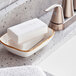 A soap dish on a white counter with Ivory bar soap in it.