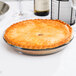 An Anchor Hocking glass pie pan with a pie on a white table.