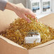 A hand opening a box filled with Spring-Fill Gold Metallic Crinkle Cut paper shred.