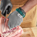 A person wearing a Schraf stainless steel mesh glove cutting meat with a knife.