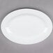 A Tuxton bright white china platter with a wide white rim on a gray surface.