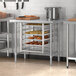 A stainless steel Regency open base work table with metal shelves holding a tray of pastries.